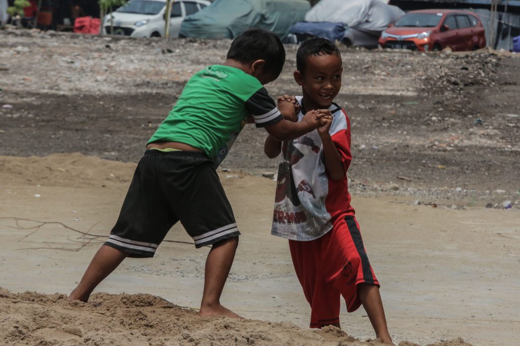 Anak kecil yang bermain di atas tumpukan pasir.
